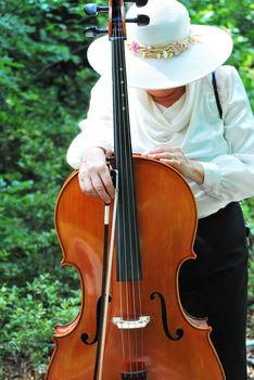 Mature female cellist with her instrument outside.