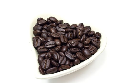 Black coffee beans in heart shaped bowl.