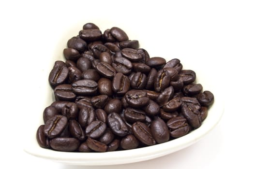 Black coffee beans in heart shaped bowl.