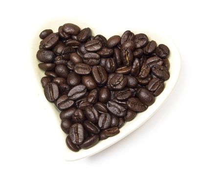 Black coffee beans in heart shaped bowl.