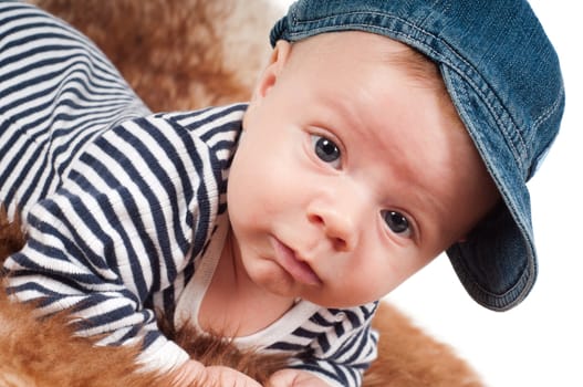 Shot of newborn baby  in denim cap lying on fur