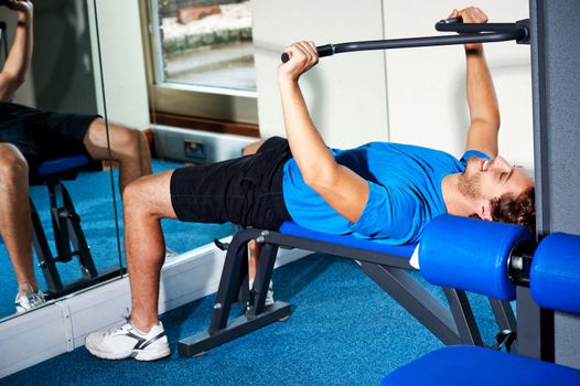 Fitness guy lying on bench and exercising, burning calories