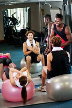 Trainer instructing gym clients on how to use exercise ball to effectiveness
