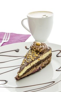 Chocolate cake served on a decorated plate. Coffee in a white cup in background.