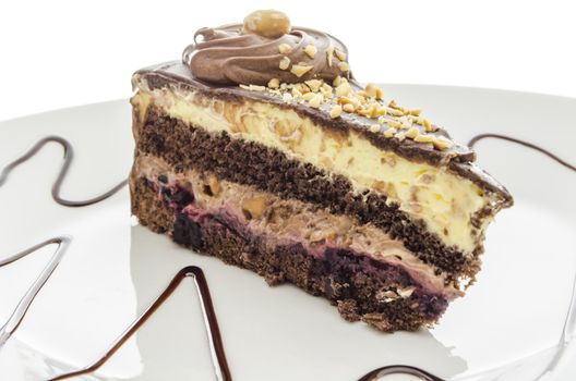 Chocolate cake closeup with hazelnuts served on a decorated plate.