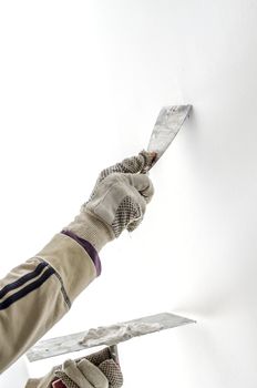 Closeup of a man aligning a wall with spatula and trowel.