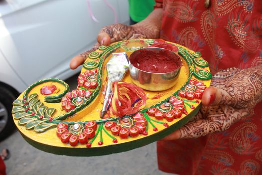 A decorated dish full of different objects related to the mehendi ritual in traditional hindu and jain marriages.