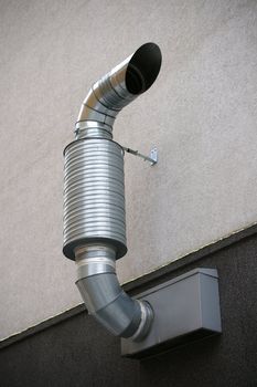 Pipe of ventilation is located on a wall of a building