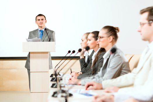 businessmen communicate at the conference, sitting at the table, focus on presenter