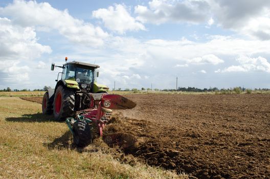 heavy agricultural equipment machine tractor works in rural farm field.