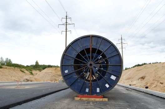 huge high voltage cable reels power line construction site. road building work and electricity line laying underground.