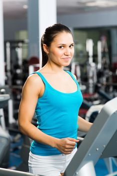 attractive young woman runs on a treadmill, is engaged in fitness sport club