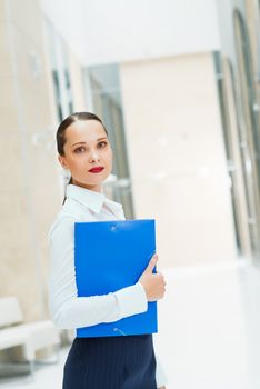 beautiful business woman standing in office, holding folder with documents