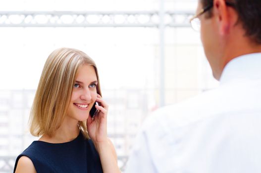 business male and business female discuss reports, Woman talking on cell phone