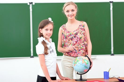 teacher explains the lesson in geography, stand near the school globe