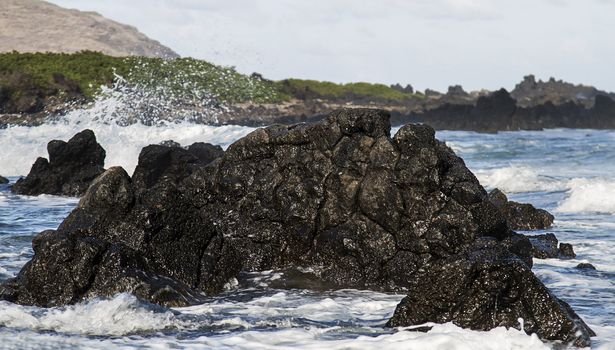 Volcanic rock in the ocean being pounded by the waves