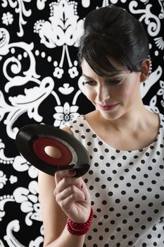 young woman reading the label of a small record