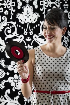 young woman smiling at the label of a small record