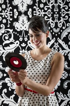 young woman with stylist clothes smiling at the label of a small record