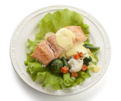 Steamed fillet of salmon with vegetables, lettuce and sauce on the white plate