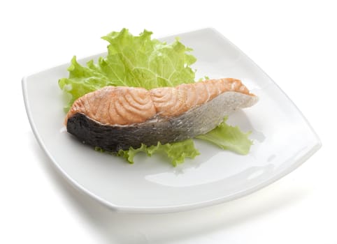 Steamed fillet of salmon with fresh lettuce on the white plate