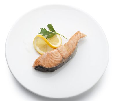 Piece of salmon's fillet with fresh lemon and parsley on the white plate