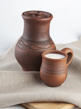 Jug and mug with milk on the tablecloth