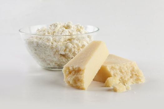 Two pieces of hard cheese and curds in the glass bowl
