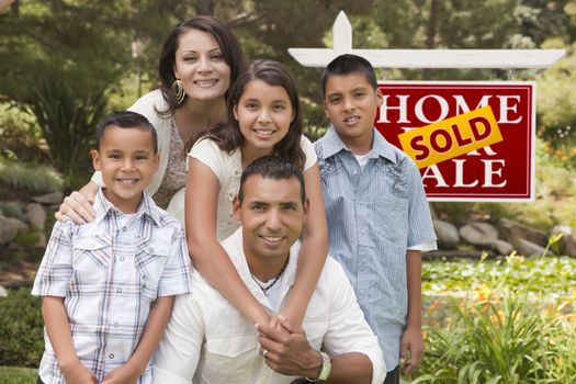 Happy Hispanic Family in Front of Sold Home for Sale Real Estate Sign.