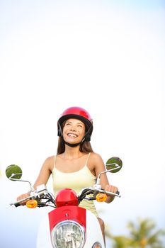 Woman on scooter thinking looking up at sky with copyspace. Happy multiracial woman driving scooter outdoor in summer.