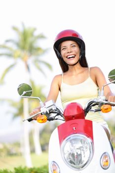 Free woman riding scooter happy. Beautiful asian woman joyful going on adventure riding scooter motorcycle on summer vacation holiday. Mixed race Asian Chinese / Caucasian girl.