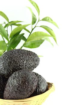 Avocados with leaves on a Dish of straw