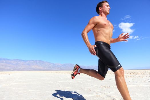 Athlete running sport - fitness runner sprinting in desert shirtless. Fit sports model man during sprint run at great speed under burning sun.