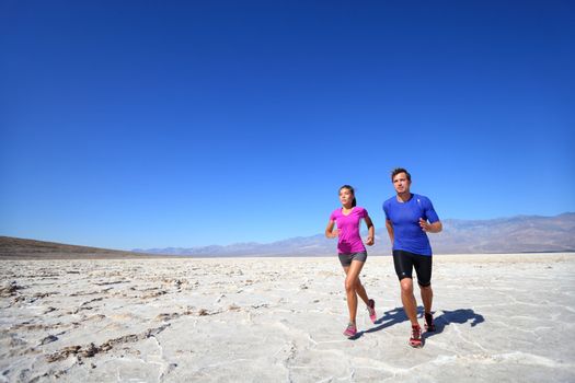 Athletes running sport fitness couple outdoor. Multiracial couple of runners training outdoors in fitness clothing under burning sun in desert. Caucasian man runner and Asian woman training.