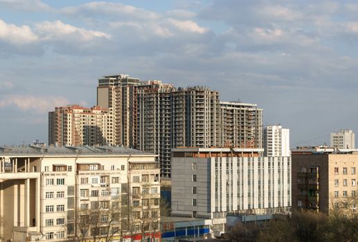 Row of living houses and unfinished new building behind under construction