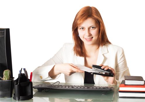 girl holds a paper stapler sitting at a table on a white background isolated