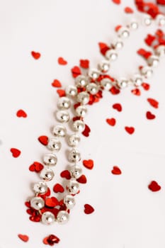 Red glitter hearts on a white background with pearls