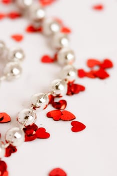 Red glitter hearts on a white background with pearls