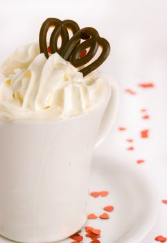 Coffee cup on a white background with red glitter hearts, cream and chocolate hearts