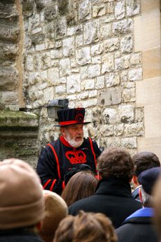 Tourists are listening to a guard at the Tower of London