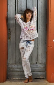 View of a beautiful girl in the beach standing against a house.