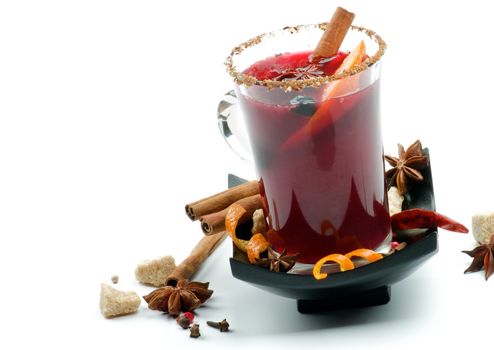 Glass of Mulled Wine and Arrangement of Cinnamon Stick, Orange Rind, Anise Star, Brown Sugar and Spices on Black Saucer closeup on white background