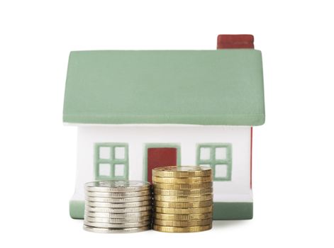Little house toy and two stacks of coins isolated over white background