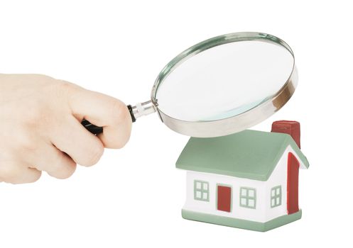 Toy of house and hand with magnifying glass isolated over white background
