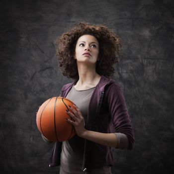 Portrait of young beautiful woman holding a basketball