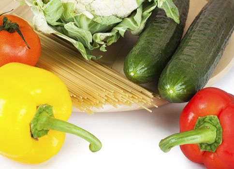Vegetables (pepper, tomato, caulflower, cucumber) and spaghetti over white background