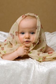 Baby lies on blanket and look to camera