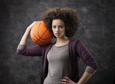 Portrait of young beautiful woman holding a basketball