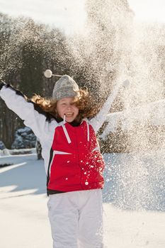 Happy teenager girl in a winter park throwing snow up - motion blur on girl's face