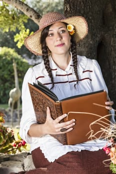 View of a beautiful girl in a classic dress reading a story book.